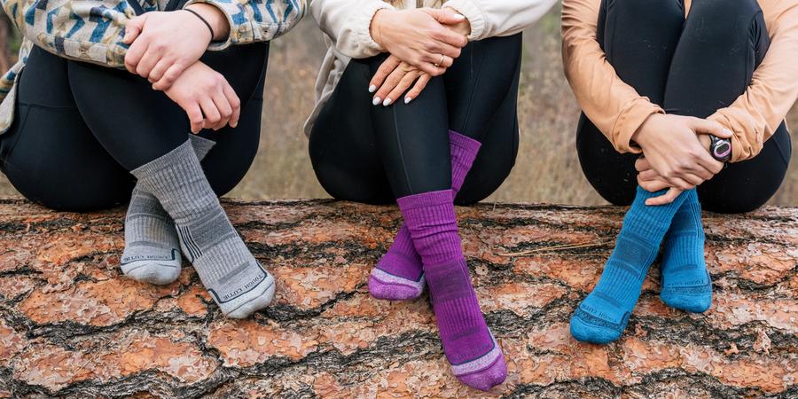 Three people sitting outside with their legs crossed wearing wool socks