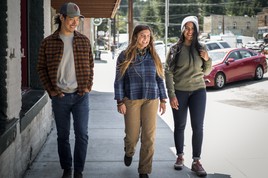 Three people walk through a town on paved roads